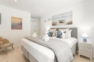 ein Schlafzimmer mit einem großen weißen Bett und einem Stuhl in der Unterkunft Oceanview Dreamer's Delight in Nazaré