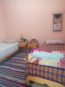 Cette chambre comprend 2 lits et une table. dans l'établissement auberge djebel rose 2, à Tafraout