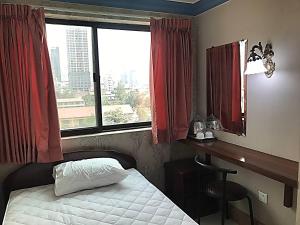 a bedroom with a bed and a desk and a window at RS Galaxy HOTEL in Phnom Penh