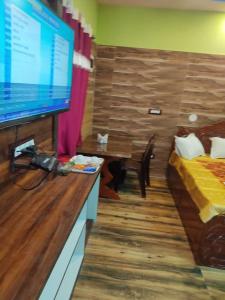 Habitación con TV, cama y mesa. en Hotel Paradise, en Mandarmani
