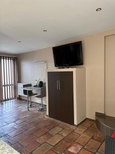 Habitación de hotel con TV de pantalla plana en la pared en La Chambre de l'Olivier en Champigny-sur-Marne