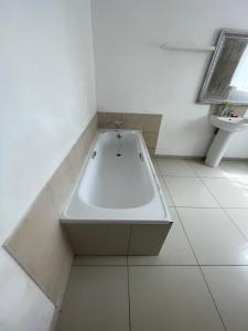 a white bath tub in a bathroom with a sink at Khaya Mnandi Leisure Suites in Pretoria