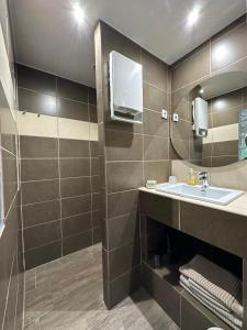 La salle de bains est pourvue d'un lavabo et d'un miroir. dans l'établissement La Chambre de l'Olivier, à Champigny-sur-Marne