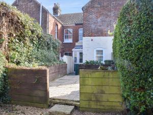 an entrance to a house with a hedge at Fuchsia Cottage in Sea Palling