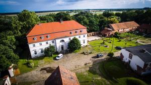 - une vue aérienne sur un grand bâtiment blanc avec un toit orange dans l'établissement Gutshof Kehnert - Pension & Ferienwohnungen, à Kehnert