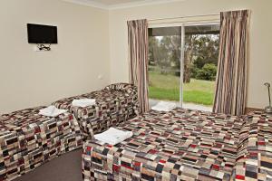 un soggiorno con divano, letto e finestra di BATHURST GOLDFIELDS MOTEL at 428 CONROD STRAIGHT MOUNT PANORAMA a Bathurst