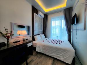 a bedroom with a bed and a desk and a window at Hanoian Hotel in Hà Ðông