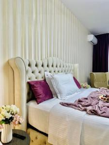 een slaapkamer met een groot wit bed met paarse kussens bij Sky Garden Panoramic View in Boekarest