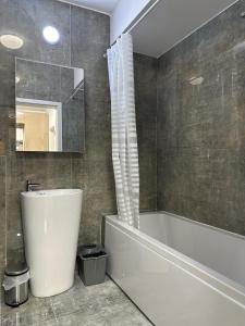 een badkamer met een bad, een wastafel en een spiegel bij Sky Garden Panoramic View in Boekarest