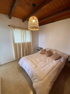 een slaapkamer met een groot wit bed en een kroonluchter bij Complejo Arenas in Alta Gracia