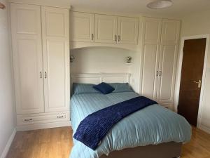 Clashmelcon的住宿－Aimee's Place，卧室内的一张床位,配有白色橱柜和蓝色毯子