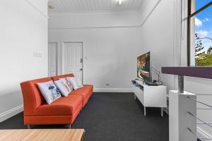 a living room with an orange couch and a tv at Private Windsor House Studios Apartment in Brisbane