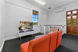 ein Wohnzimmer mit einem orangenen Sofa und einem TV in der Unterkunft Private Windsor House Studios Apartment in Brisbane
