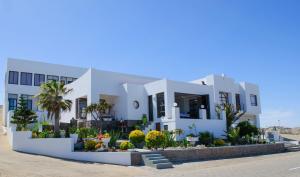 a white house with plants in front of it at Shark Island Guesthouse in Lüderitz