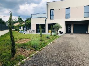 a house with a dog standing outside of it at Villa piscine 6 personnes in Meyzieu