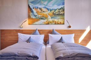 zwei Kissen auf einem Bett mit einem Gemälde an der Wand in der Unterkunft Hotel Aschenbrenner in Garmisch-Partenkirchen