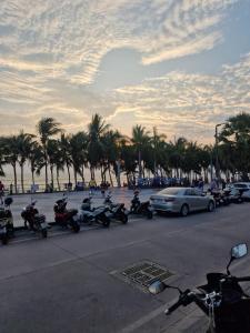 a group of motorcycles parked in a parking lot with palm trees at Paradise Bar and Guesthouse 1 in Pattaya South