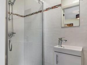 a white bathroom with a shower and a sink at Lovely Primrose Cottage Torquay in Torquay