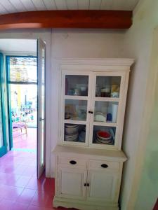 um armário branco com pratos ao lado de uma porta em La casa sul porto - Marina Grande port em Procida