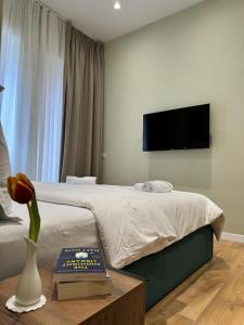 Un dormitorio con una cama y un jarrón con una flor en una mesa en Vila Panto, en Tirana