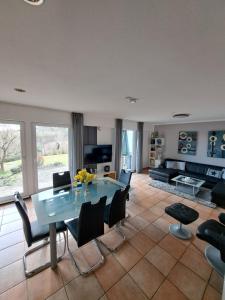 een woonkamer met een glazen tafel en stoelen bij Ferienhäuser Rhön - Haus Natalie & Haus Helene in Hausen