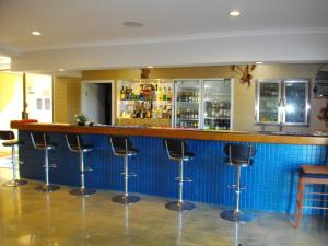 eine Bar mit Hockern vor einer blauen Theke in der Unterkunft Kurrimine Beach Motel in Kurrimine Beach