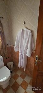 a white robe hanging in a bathroom with a toilet at شقة هادئة بمساحة كبيرة بحي التنعيم بمكة المكرمة غرفة نوم واحدة فقط in Murshidīyah