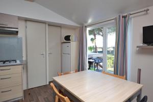 uma cozinha com uma mesa com cadeiras e uma sala de jantar em La Marine 4* - Mobil Home 3ch - 6 couchages em Le Grau-du-Roi