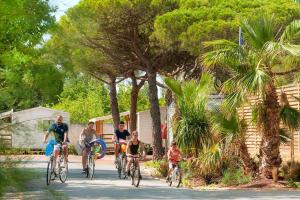 um grupo de pessoas andando de bicicleta por uma rua em La Marine 4* - Mobil Home 3ch - 6 couchages em Le Grau-du-Roi