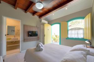 a bedroom with a white bed and a bathroom at Pousada Vila do Porto in Paraty