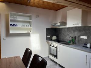 a kitchen with white cabinets and a wooden table at FerienWohnung A&S Heuchelheim in Heuchelheim