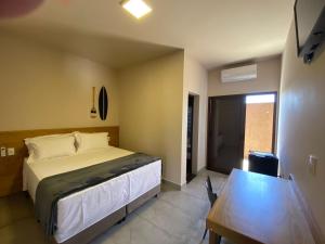 a bedroom with a large bed and a table at POUSADA MALA E CUIA in Rifaina