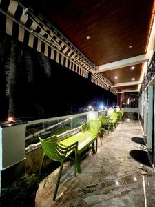 a row of green tables and chairs on a balcony at night at EMINENCE - PALM RESIDENCY (1.5 KM FROM NAKKI LAKE) in Mount Ābu