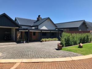 a house with a brick driveway in front of it at Highland Gate Belhaven in Dullstroom