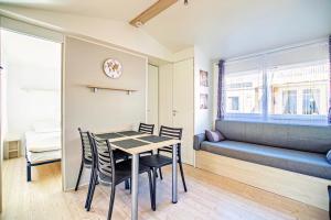 a dining room with a table and chairs and a couch at Mobil-Home Valras plage in Valras-Plage