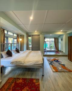 um quarto com uma cama grande num quarto com janelas em Eevolve Dharamkot - An Eco Hostel em McLeod Ganj