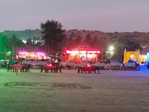 un gruppo di tavoli e sedie su una spiaggia di notte di Euphoria Studioz a Mandrem