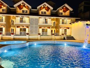 una piscina frente a un hotel por la noche en The Grand Leela Resort, en Khopoli