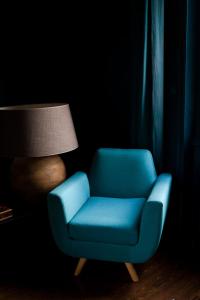 a blue chair sitting in a room with a lamp at Le Jardin, chambres d'hôtes en Baie de Somme in Cahon