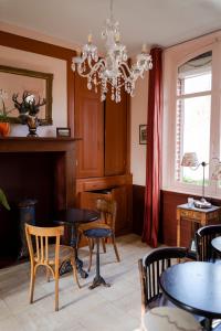 ein Esszimmer mit Tischen, Stühlen und einem Kronleuchter in der Unterkunft Le Jardin, chambres d'hôtes en Baie de Somme in Cahon
