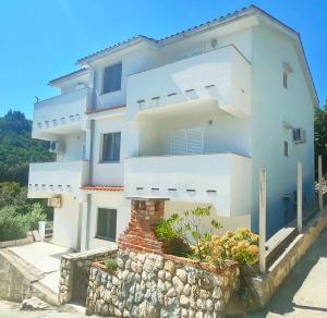 a white house with a stone wall at Rab Island Apartments Del Sole in Supetarska Draga