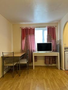 Specious 1 Bed Apartment free wifi and parking في Goodmayes: غرفة مع طاولة ومكتب مع تلفزيون