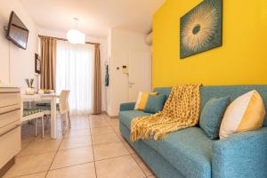 Una sala de estar con un sofá azul y una pared amarilla. en Villaggio Evanike, en Bibione