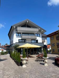 a building with tables and chairs and a yellow umbrella at FeWo Zirbenruhe: zentral & modern mit Naturflair in Oberstaufen