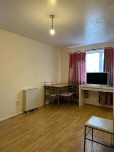 a living room with a table and a desk with a computer at Specious 1 Bed Apartment free wifi and parking in Goodmayes