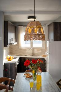 a kitchen with a table with flowers and aendant light at Aggeliki House in Kissós