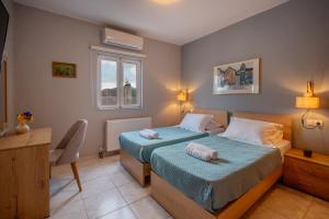 a bedroom with two beds and a desk and a window at House Aggeliki Private Hot Tub in Kissós