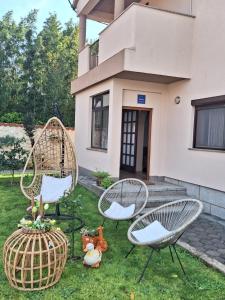 drie stoelen en een mand in het gras voor een huis bij Apartmani Zara & Duje in Bibinje