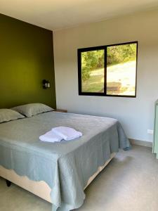 Un dormitorio con una cama grande con ventana. en Suítes Por do Sol, en Cabreúva