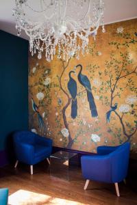 une peinture d'oiseaux sur un mur avec deux chaises bleues dans l'établissement Le Jardin, chambres d'hôtes en Baie de Somme, à Cahon